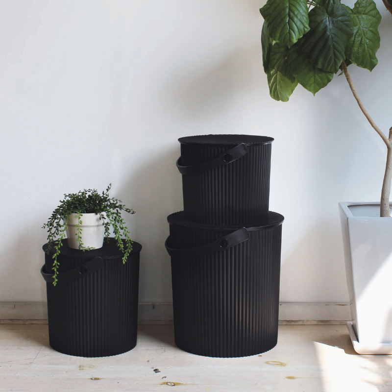 Aufbewahrungs-Eimer Hachiman in der Farbe Schwarz neben einem Blumenkübel